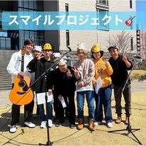 「スマイルプロジェクト」のロゴが入った、屋外での演奏の記録写真