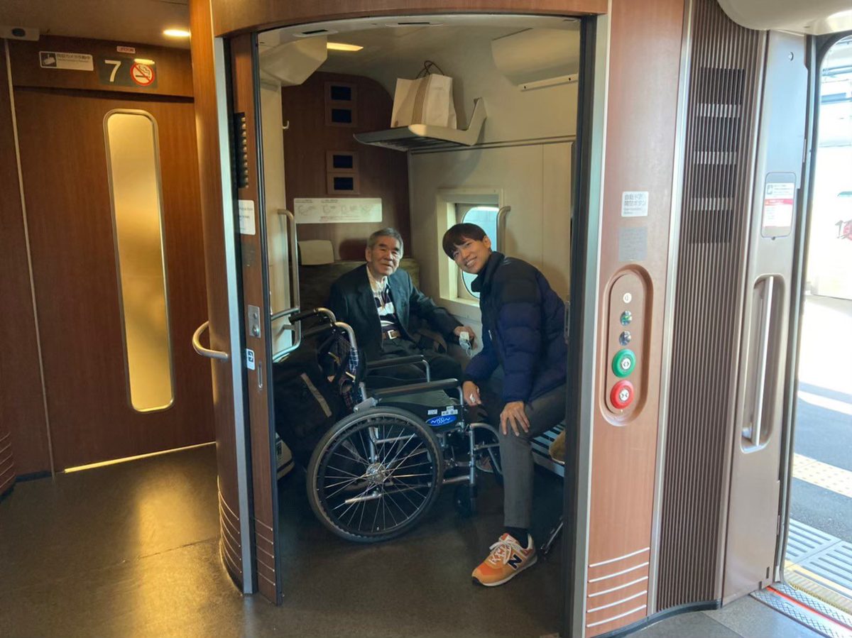 新幹線の車いす対応席の扉が開いた状態で、車いすの男性と福田真悟が並んで笑顔