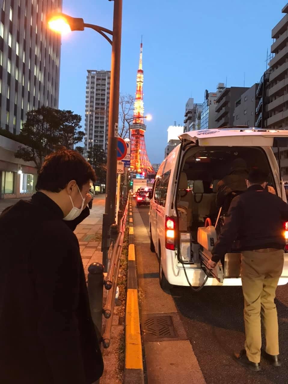 夕暮れの東京タワーを正面に、リフト付きの福祉車両の後部から乗り降りしている